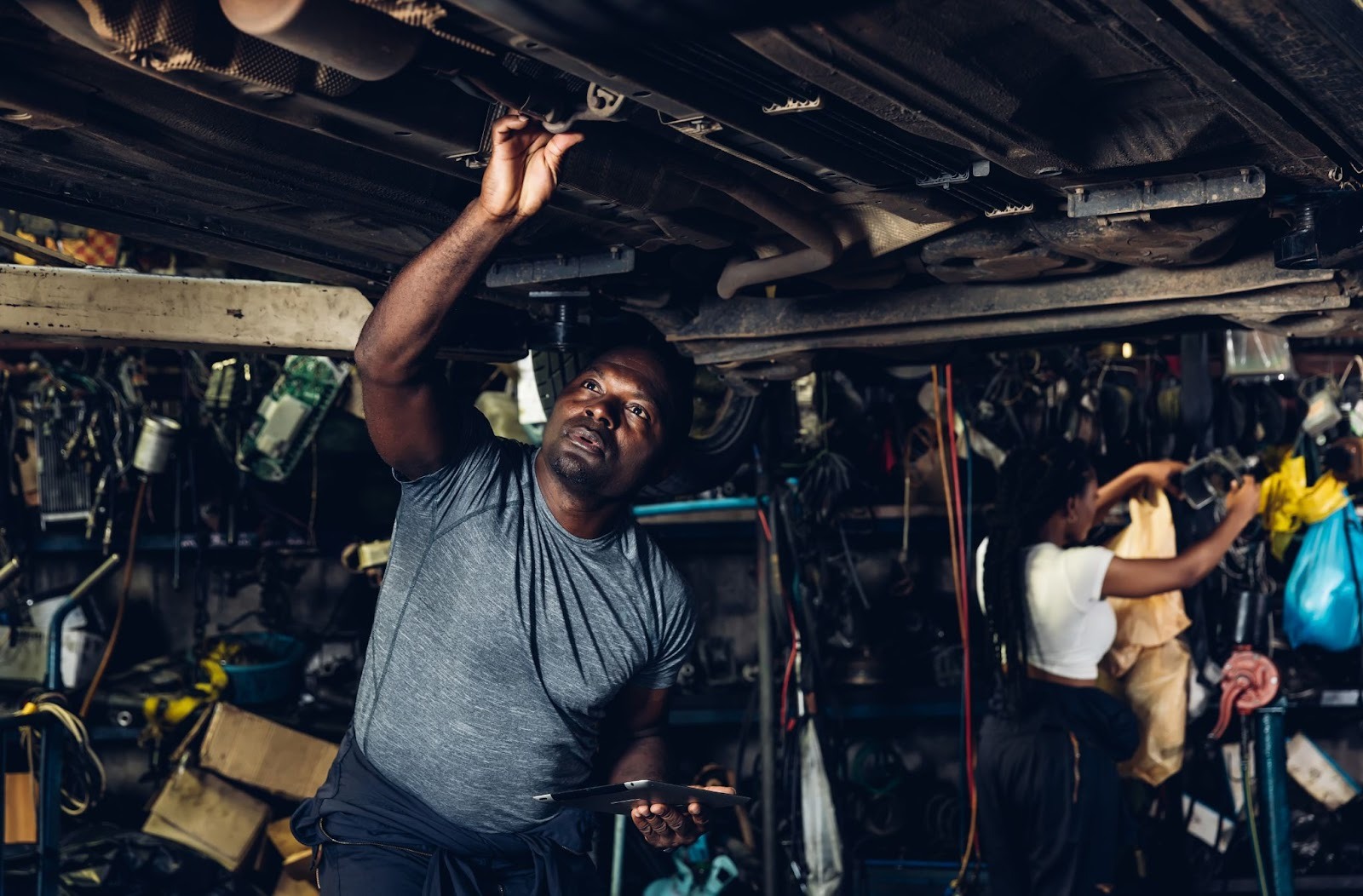 A mechanic searches underneath a car while performing transmission service.