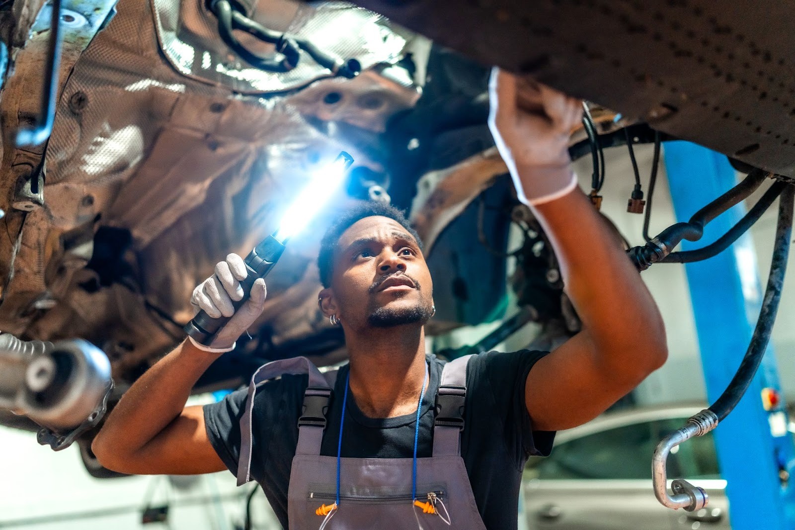 Mechanic performing a chassis inspection with a flashlight at an auto repair shop