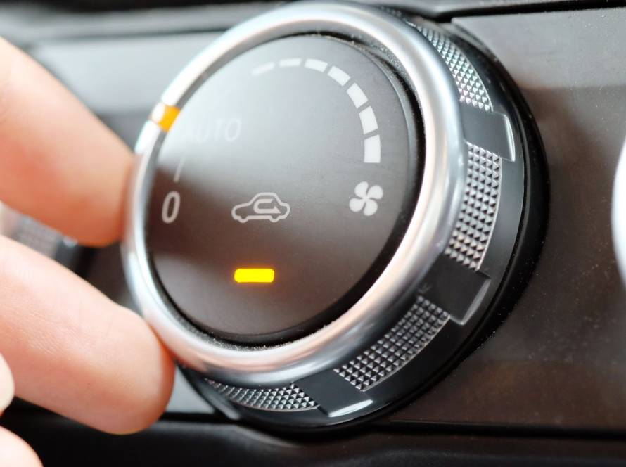 Close-up of a hand adjusting a vehicle air conditioning control to regulate cabin temperature