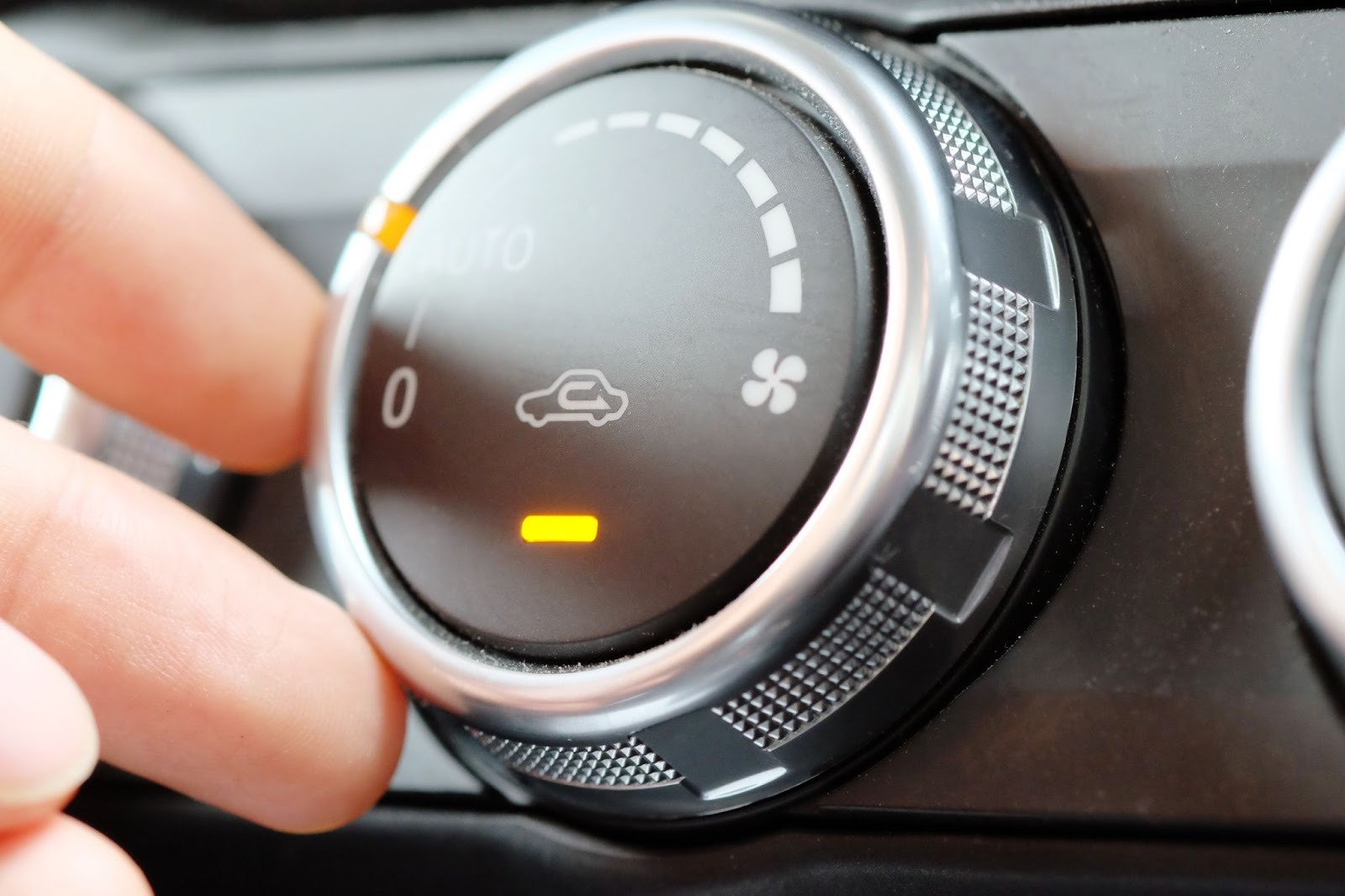 Close-up of a hand adjusting a vehicle air conditioning control to regulate cabin temperature