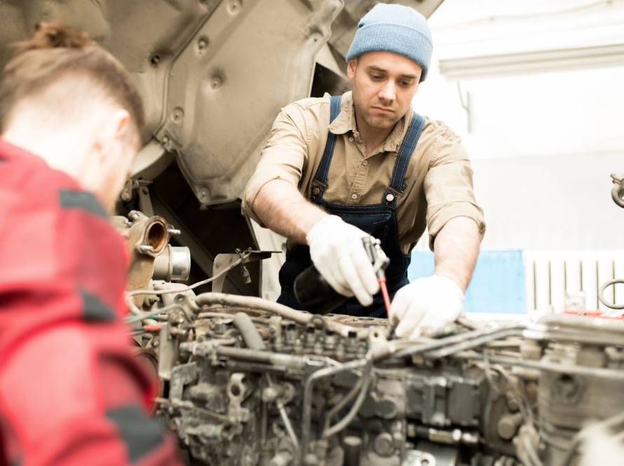 Auto technicians working on a diesel engine during scheduled maintenance