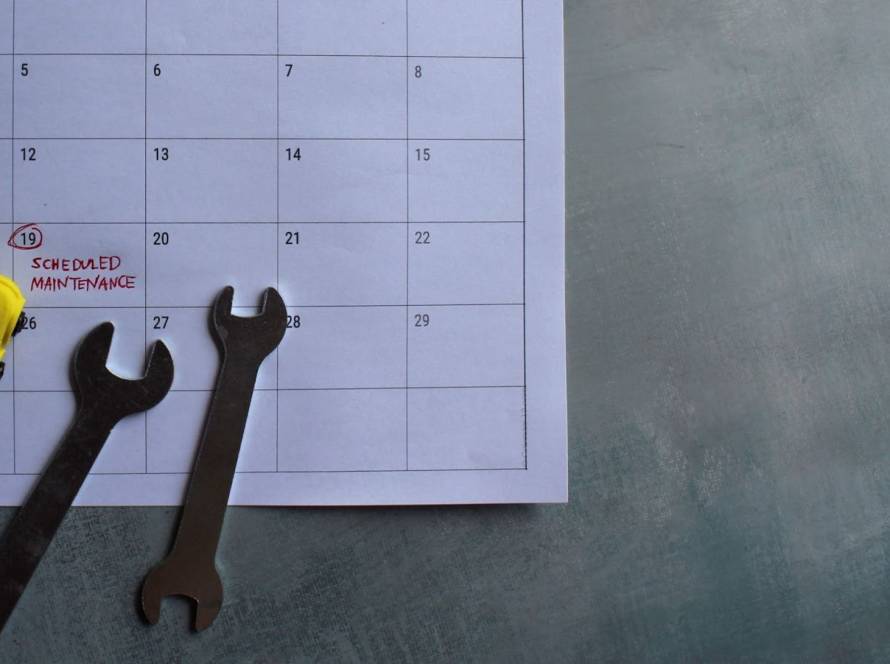 Toy vehicle and wrenches on a marked calendar highlighting scheduled maintenance dates