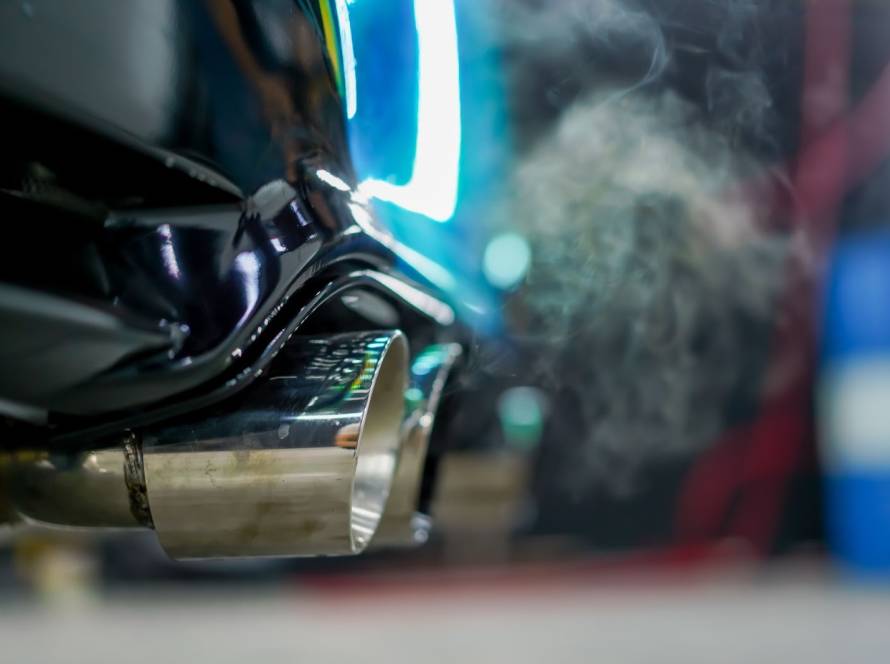 Detailed view of smoke coming from the exhaust pipe of a chameleon-painted high-end vehicle